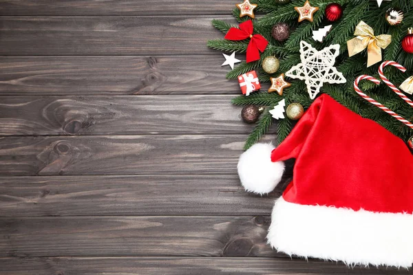 木のテーブルの上におもちゃやサンタの帽子とクリスマスツリーの枝 — ストック写真