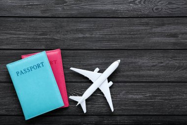 Siyah ahşap masada pasaportlu uçak modeli.