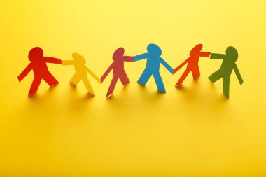 Sarı arka planda renkli kağıt zincir insanları