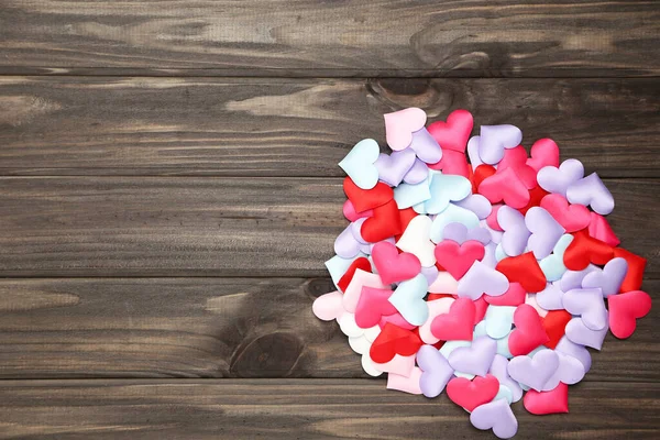 Colorful small hearts on brown wooden background