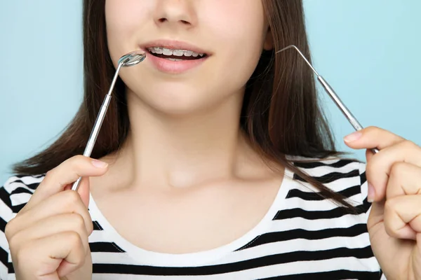 Mladá dívka s chrup rovnátka drží zubař nástroje na modrých zádech — Stock fotografie