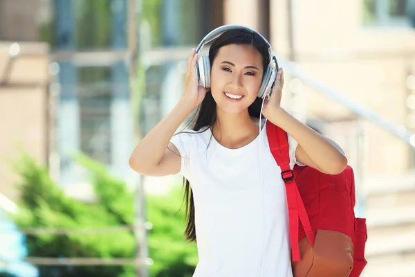 Hermosa joven con auriculares y mochila en la calle — Foto de Stock