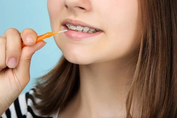 Chica joven con frenos dentales sosteniendo el cepillo de dientes en el backgro azul — Foto de Stock