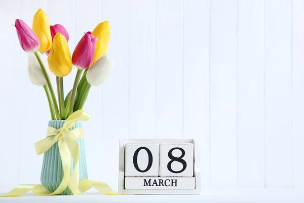 Bouquet of tulip flowers in vase with calendar on white backgrou — Stock Photo, Image