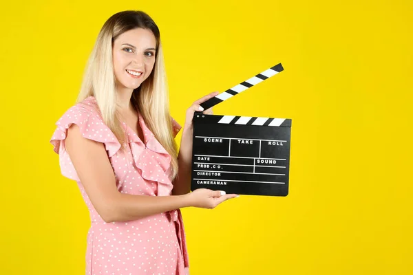 Mladá žena s prázdným tleskací desky na žlutém pozadí — Stock fotografie