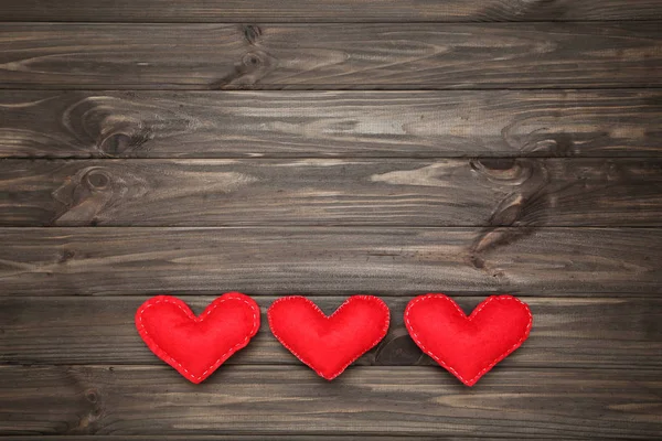 Red fabric hearts on brown wooden table — Stock Photo, Image