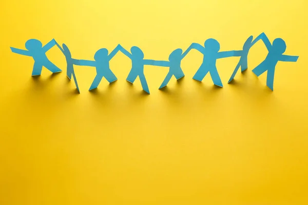 Paper chain people on yellow background — Stock Photo, Image