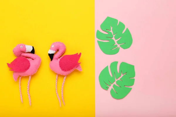 Zacht speeltje van flamingo 's met groene papieren blaadjes op kleurrijk papier b — Stockfoto