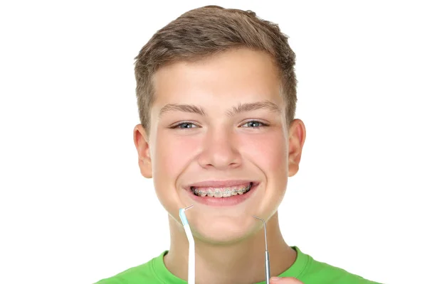 Mladý muž s kartáčkem na zuby a zubař nástroj na bílém pozadí — Stock fotografie
