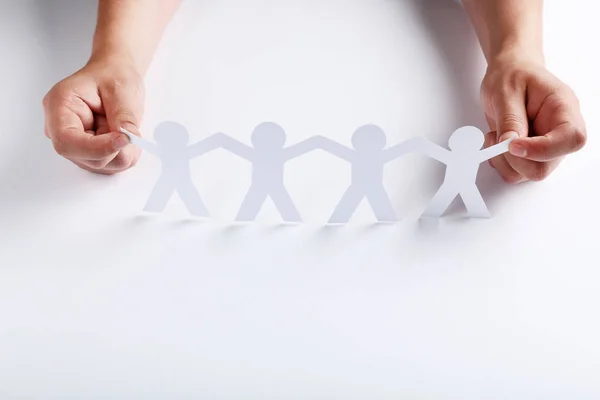 Paper chain people with female hands on white background — Stock Photo, Image