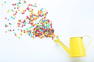 Renkli kalp şeklinde serpintiler beyaz arka planda sulama tenekesi