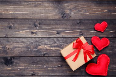 Kurdeleli hediye kutusu ve tahta masada kalpler.