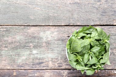 Kase gri ahşap masa üzerinde yeşil fesleğen yaprakları