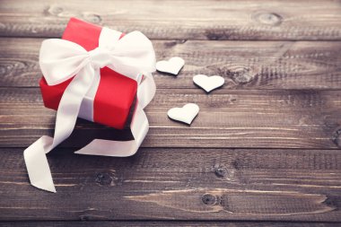 Kurdeleli hediye kutusu ve kahverengi ahşap masada kalpler.
