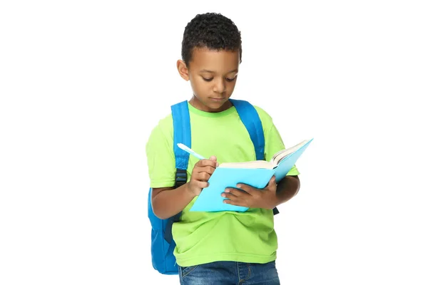 Jonge Afro-Amerikaanse schooljongen schrijven in notitieblok met backpa — Stockfoto