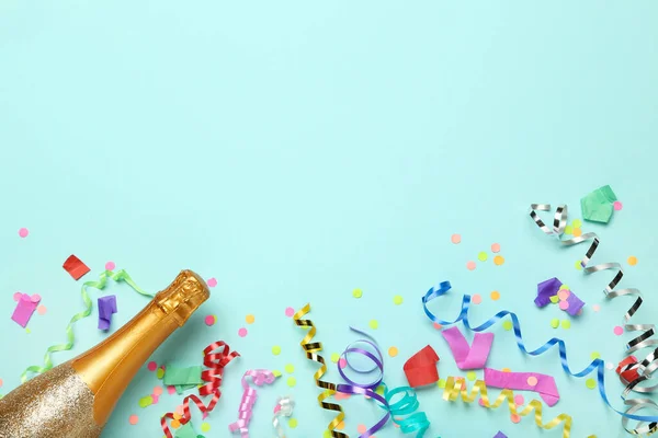 Colorful ribbons with confetti and champagne bottle on blue background
