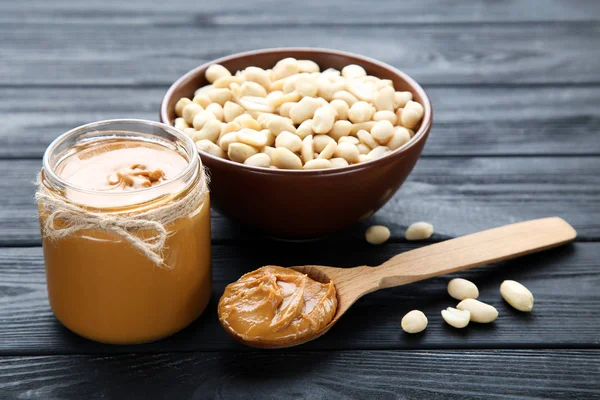 Fıstık ezmesi ve fındık, siyah ahşap masada.