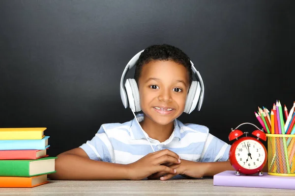 Jonge Afro-Amerikaanse schooljongen zit aan het bureau met boeken, pe — Stockfoto