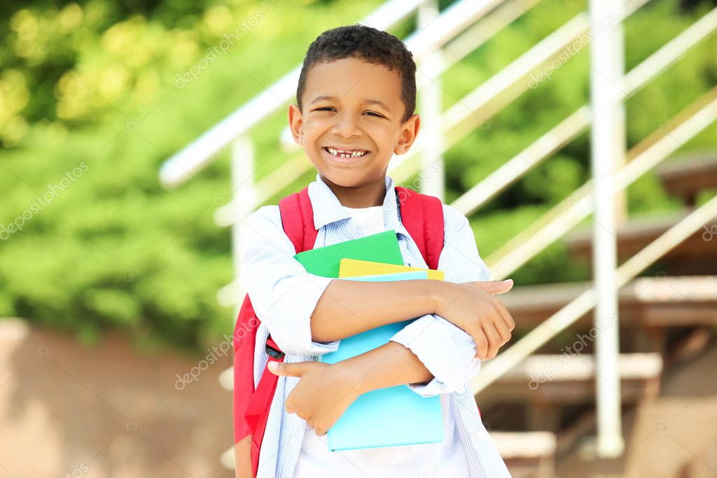 Young African American school boy with backpack and books on the