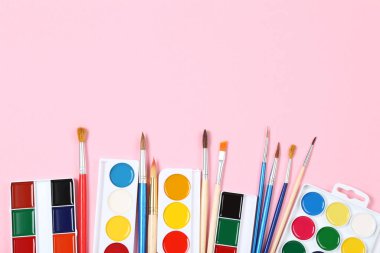 Renkli gouache pembe arka planda boya ve fırçalar