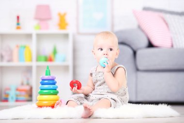 Güzel küçük çocuk oturuyor ve fahişelerde plastik oyuncaklarla oynuyor.