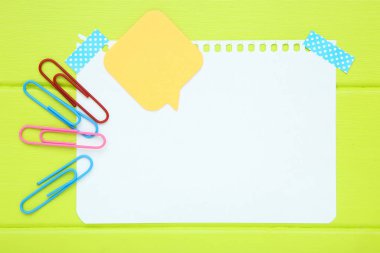 Ataşlı boş bir kağıt parçası ve yeşil ahşap masada konuşma balonu.