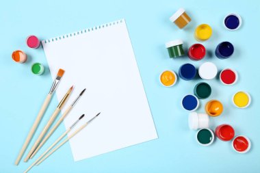 Renkli gouache ile boş kağıt yaprağı mavi arka planda boya ve fırçalar