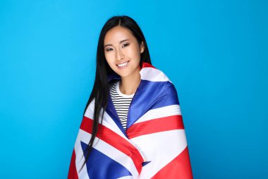 Mavi arka planda İngiliz bayrağına sarılmış genç bir kadın