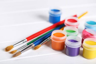 Renkli gouache beyaz ahşap masa üzerinde boya ve fırça