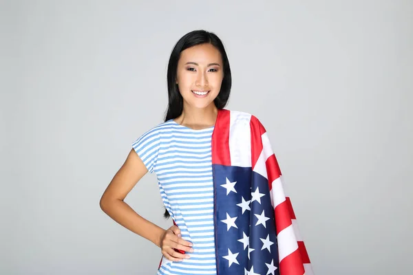 Young woman holding American flag on grey background — Stock Photo, Image
