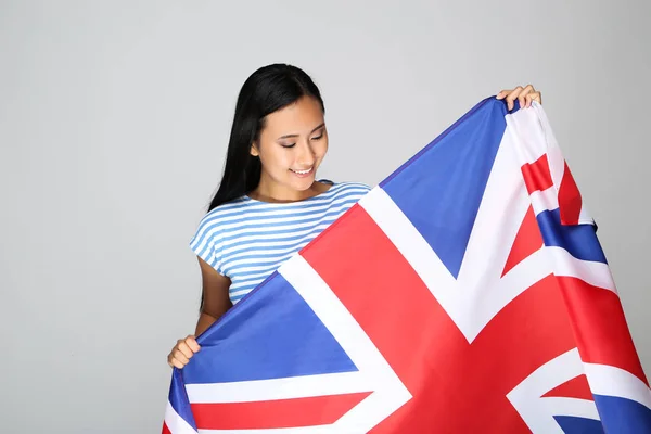 Молодая женщина с британским флагом на сером фоне — стоковое фото