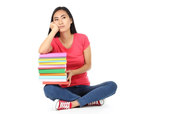 Mujer joven con pila de libros sentados sobre fondo blanco — Foto de Stock