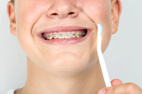 Mladý muž se zubním kartáčkem na šedém pozadí — Stock fotografie