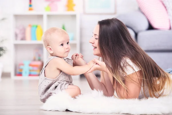 Evde halıya uzanmış bebekle birlikte genç bir anne. — Stok fotoğraf