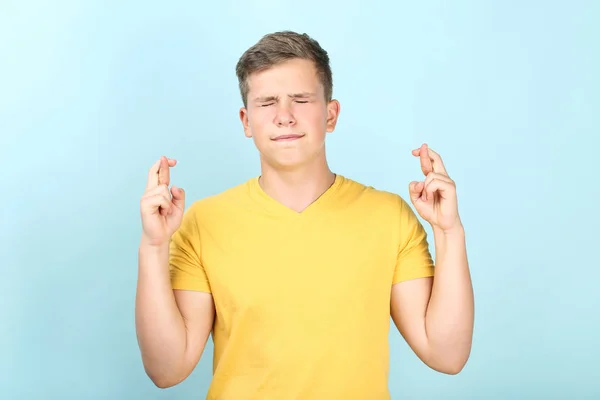 Joven cruza dedos sobre fondo azul — Foto de Stock