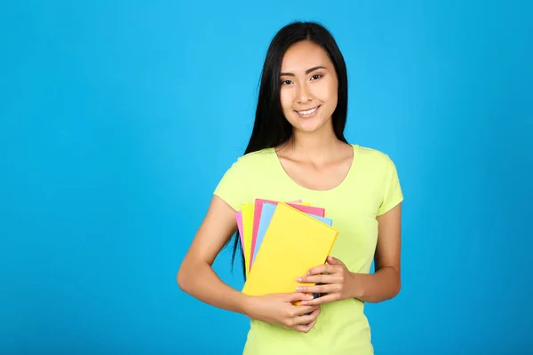 Young woman with colorful books on blue background — 스톡 사진