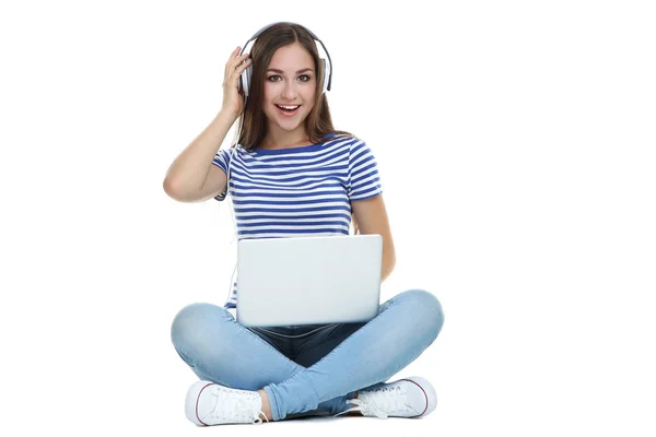 Chica joven en auriculares con ordenador portátil sentado en blanco b — Foto de Stock