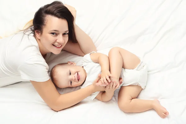 Jovem mãe com bebê menino deitado na cama — Fotografia de Stock