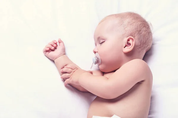 Menino bonito com chupeta dormindo na cama em casa — Fotografia de Stock