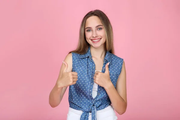 Vacker ung kvinna visar tummen upp på rosa bakgrund — Stockfoto