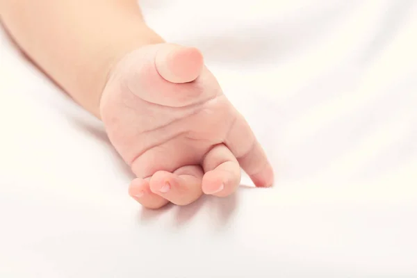 Liten babyhand på vit säng — Stockfoto