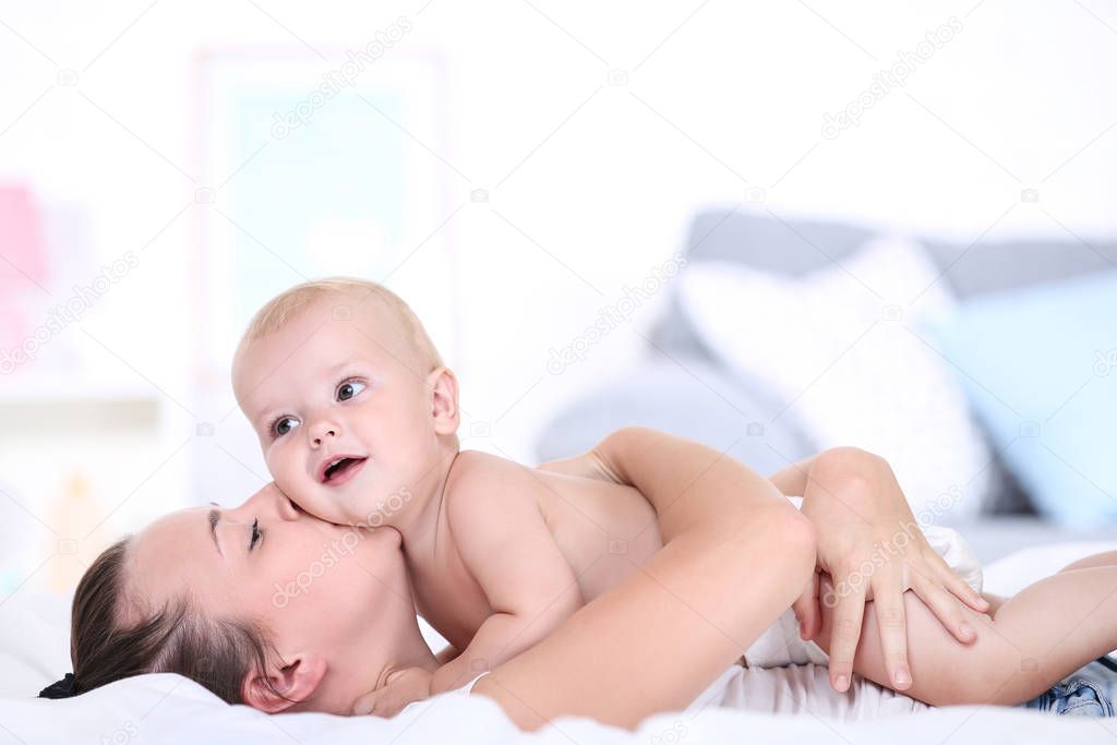 Young mother with baby boy lying on bed
