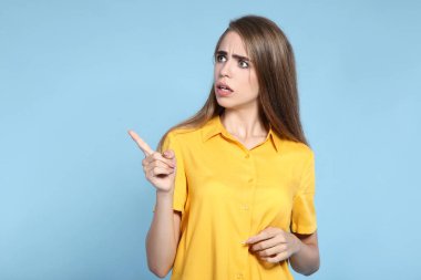 Genç ve güzel bir kız mavi arka planda parmakla görünüyor.