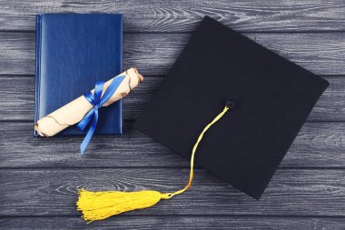 Siyah ahşap masa üzerinde diploma ve not defteri ile Mezuniyet kapağı