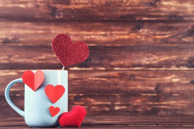 Kahverengi ahşap masada kupalı kağıt kalpler.