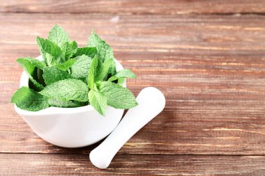 Kahverengi ahşap masada harç ile nane yaprakları