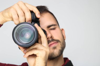 Mavi arka planda kameralı genç fotoğrafçı