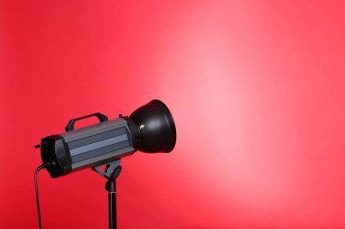 Kırmızı arkaplanda üç ayaklı stüdyo ışıklandırması
