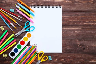 Kahverengi ahşap masa üzerinde açılan defter ile okul malzemeleri