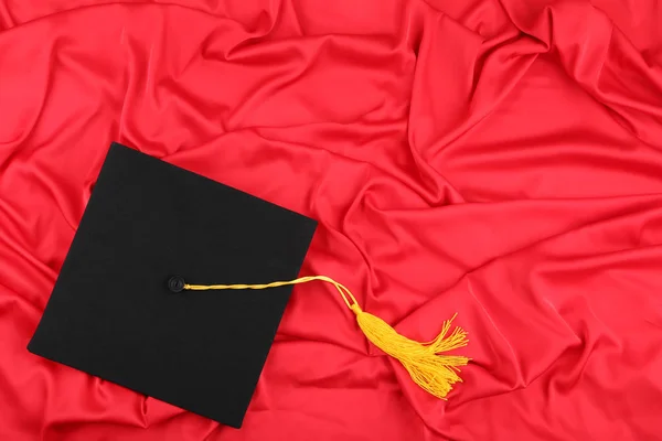 Graduation sapka piros szatén szövet háttér — Stock Fotó